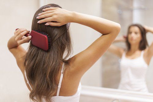 женщина, расчесывающая волосы перед зеркалом