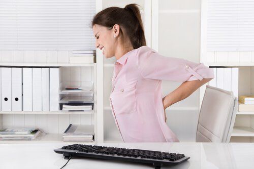 Женщина у компьютера страдает от боли в спине