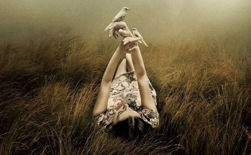 Женщина лежит на лугу и держит в руках птиц