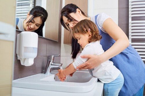 Мать моет руки своей дочери и вирус Коксаки