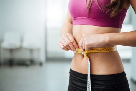 Женщина измеряет окружность талии и гормоны