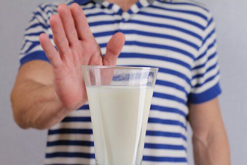 непереносимость лактозы, женщина, держащая руку на стакане молока