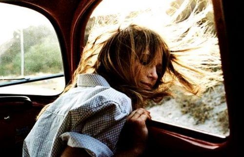 Счастливая девушка с растрепанными волосами у окна в машине
