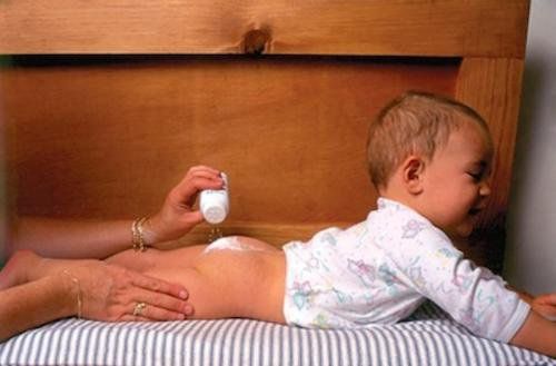 разбудить ребенка, чтобы сменить подгузники - мама, разбрызгивающая тальк с тальком