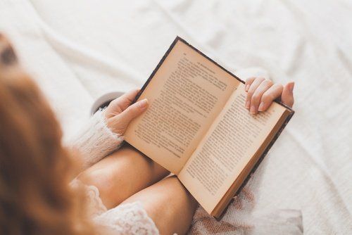 Женщина читает книгу в постели