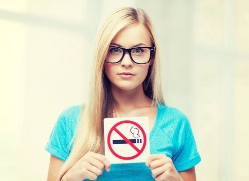 Женщина, держащая листовки, запрещенные к курению и курению сигарет