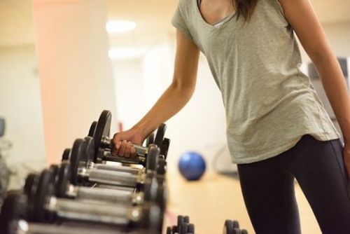 спортивная женщина поднимает тяжести, делает тренировки тела