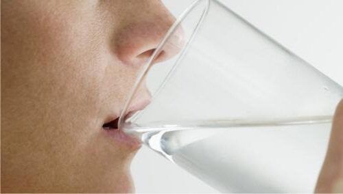 Женщина выпивает стакан воды