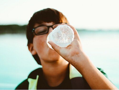 мальчик обезвоживания пьет воду из бутылки
