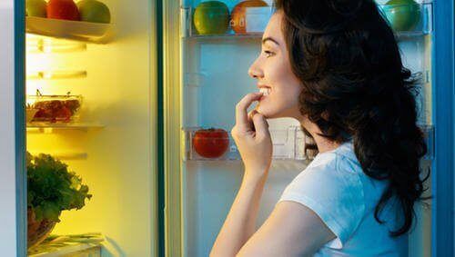 Употребляя пищевые привычки, женщина просматривает холодильник