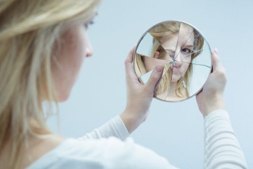 Женщина смотрит в разбитое зеркало