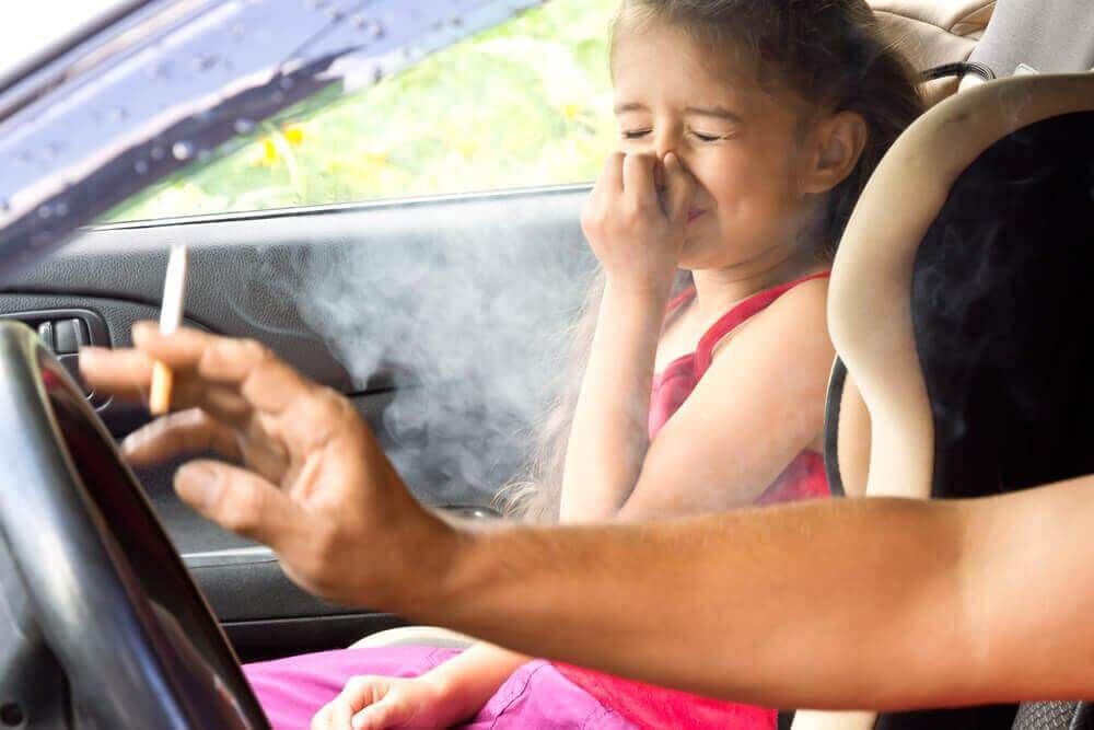 Пассивное курение и рак легких. Отец курит сигарету в машине рядом со своей дочерью