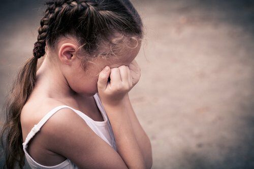 Удар причиняет боль девушке, которая плачет, закрывая лицо