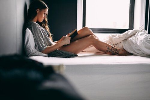 Женщина в постели читает книгу