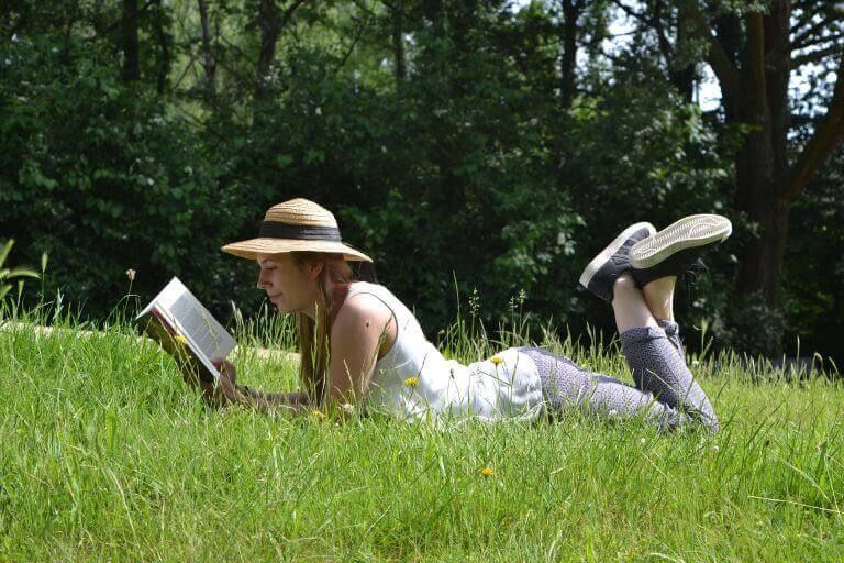 Женщина читает книгу на лугу, растения