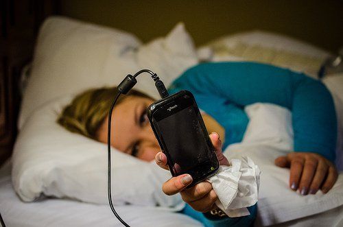 Женщина в постели с телефоном в руке