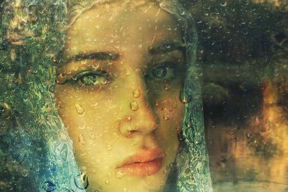 Девушка за стеклом плачет дождь.