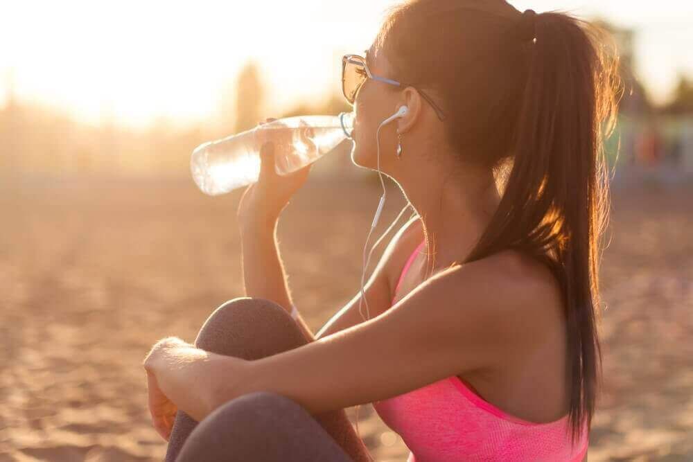 питьевая вода, женщина пьет воду на пляже