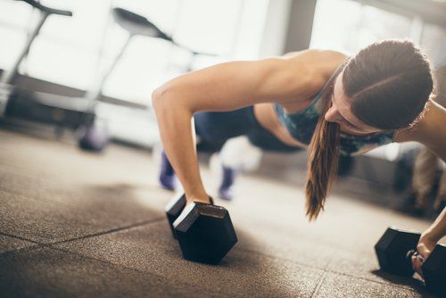 Женщина тренируется в тренажерном зале с весами