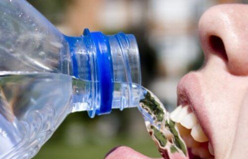 Женщина, пьющая воду из пластиковой бутылки