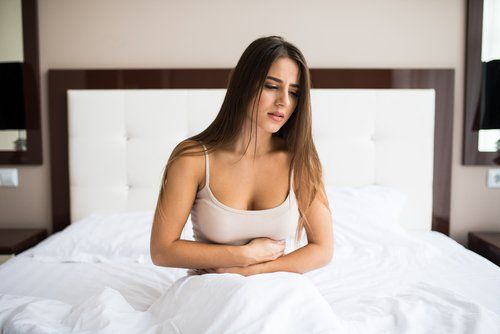 Женщина в постели страдает от боли в животе