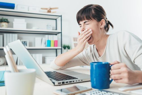 усталость надпочечников и хроническая усталость - зевая женщина с чашкой кофе и компьютером
